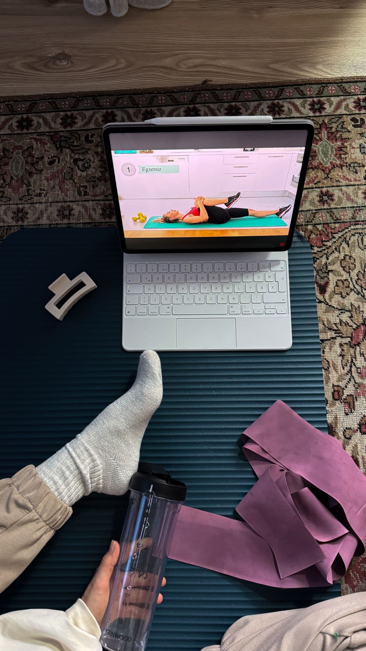 First-person view of following a guided home workout on a mat with resistance bands and a water bottle.